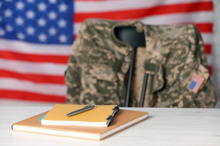 Featured image for GI Bill, showing notebooks on a table with a soldier uniform and a flag of the United States in the background