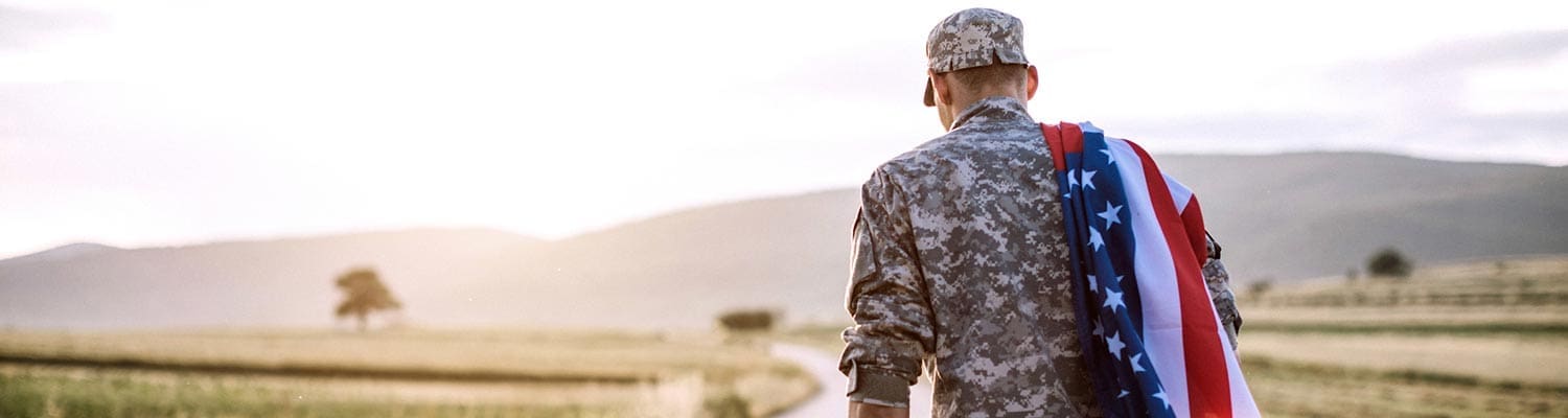 Featured image for the about page of Brave Veteran, showing a walking soldier with a flag of the United States over his shoulder